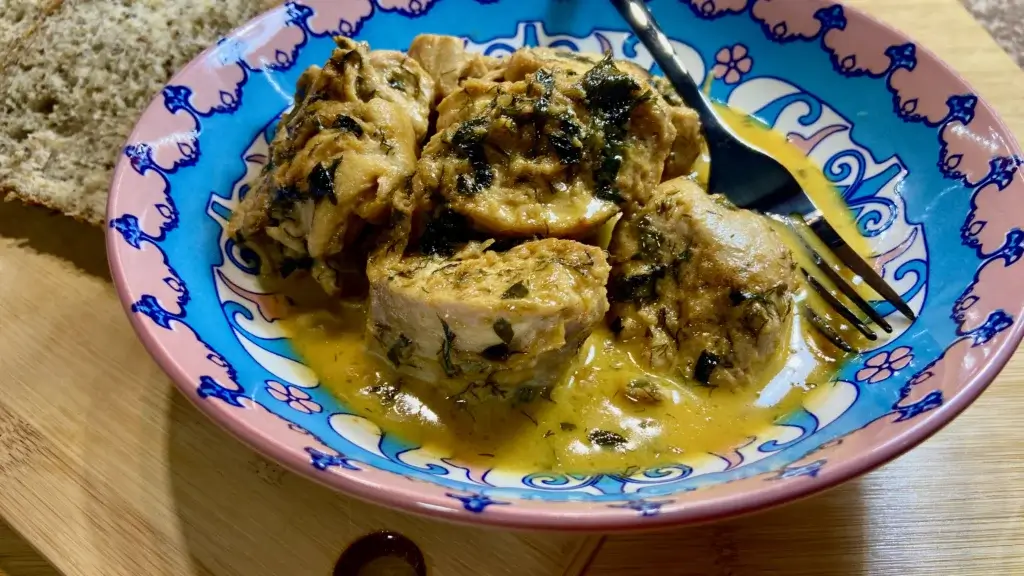 Creamy Chicken served on a plate with bread aside on a wooden board 